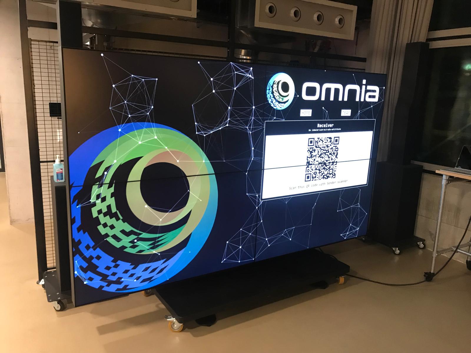 The Omnia Share receiver on the big screen in the SPH events area: the Omnia logo and a QR code to scan from the sender device in order to connect.