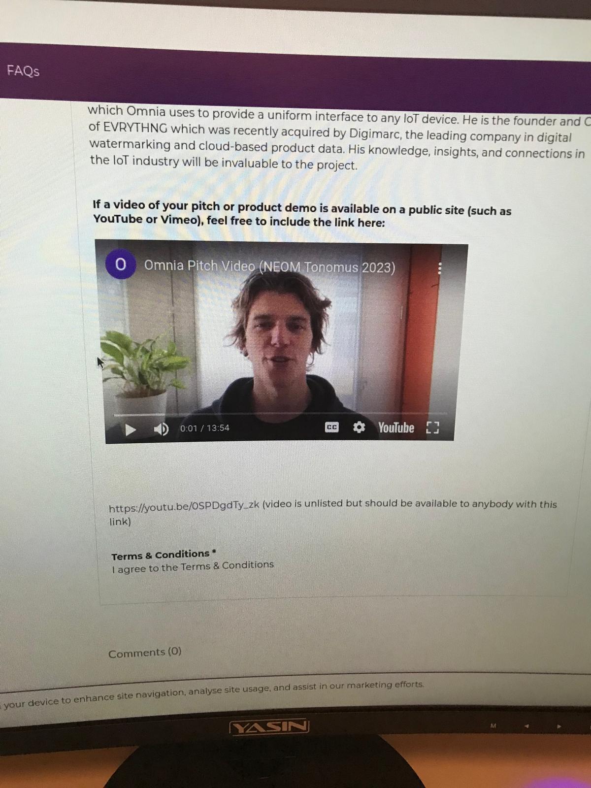 Photo of a monitor showing the same Tonomus submission's pitch-video section — an embedded "Omnia Pitch Video (NEOM Tonomus 2023)" YouTube clip of Massimo, with the unlisted youtu.be link below it.