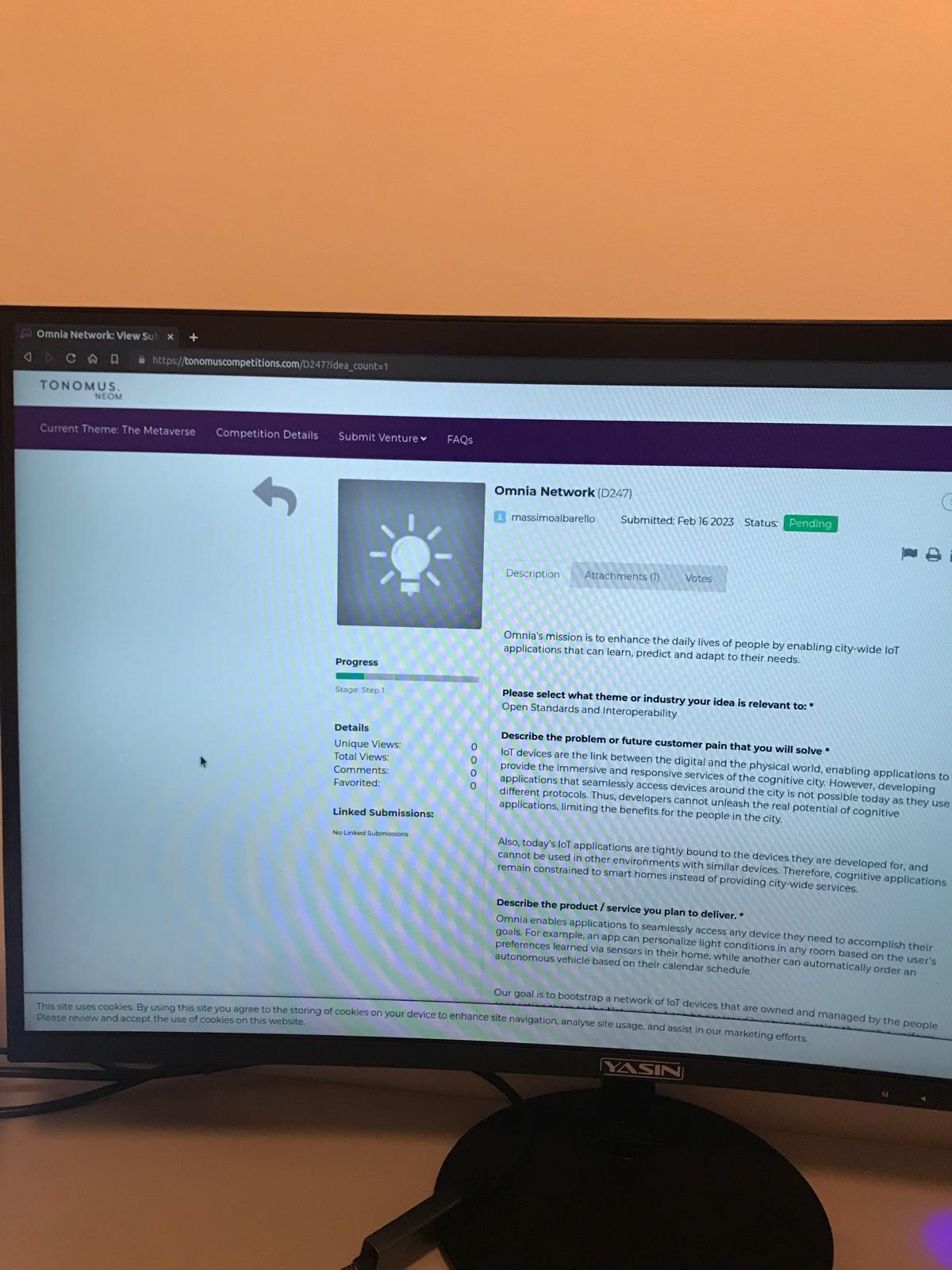 Photo of a monitor showing the Tonomus (Neom) competition portal — Omnia Network's submission (D247), submitted by massimoalbarello on Feb 16 2023 with status Pending, describing Omnia's mission to enable city-wide IoT applications that learn, predict, and adapt.