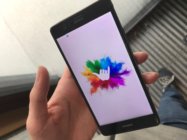 A hand holding a phone showing the SYT logo as the app's splash screen.