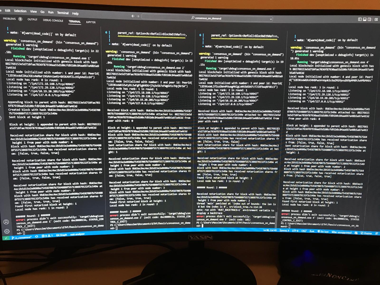 Photo of a monitor running four terminal panes in VS Code, each executing a node of the consensus_on_demand (FICC) prototype — logging genesis-block initialization, peer IDs, notarization shares, and rounds — during the first local multi-node run.